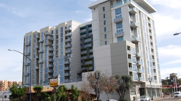 Modern apartment complex next to Father Joe's on the corner of 16th and Market, featuring multiple balconies and nearby dining.