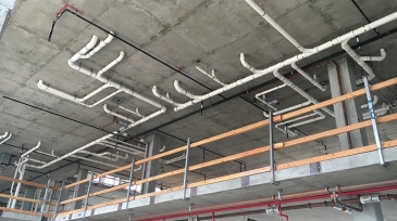 Exposed plumbing and piping under the ceiling of a construction site at Naval Base Coronado.