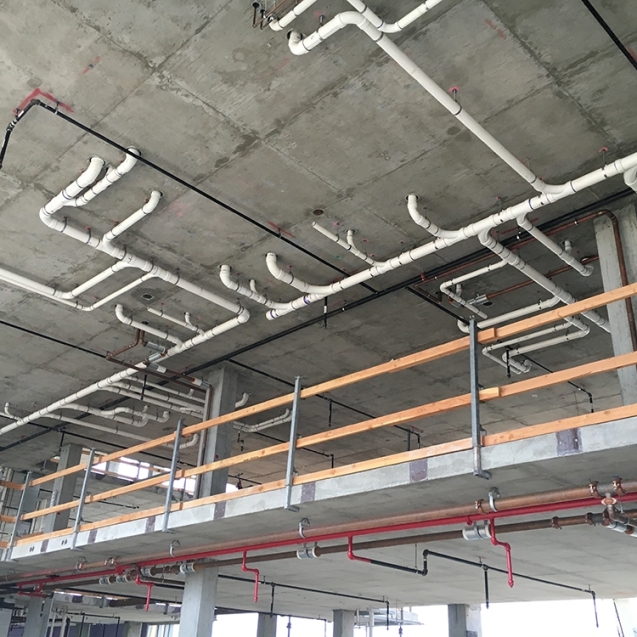 Exposed plumbing and piping under the ceiling of a construction site at Naval Base Coronado.