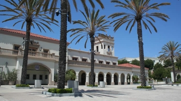 Jenny Craig Pavilion surrounded by palm trees and a landscaped plaza under a clear blue sky.
