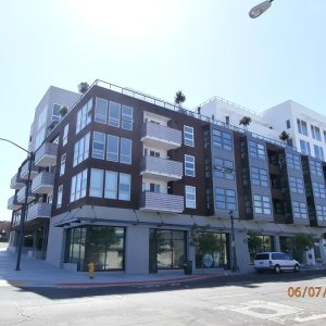 Modern residential building with balconies, featuring a mix of dark and light exterior colors in an urban setting.