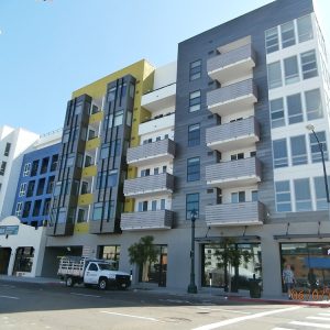 Modern apartment building with colorful balconies and street-level retail in Kettner Lofts, captured on a sunny day.