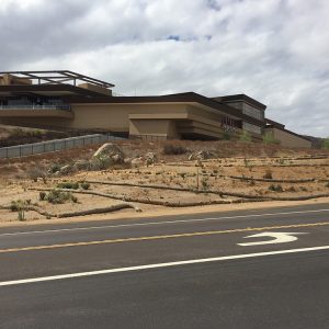 Hollywood Casino Jamul building landscape with surrounding dry terrain and hillside, showcasing modern architecture against a cloudy sky.