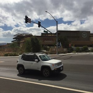 White SUV driving on a road in front of Hollywood Casino Jamul under a cloudy sky.