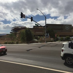 Hollywood Casino Jamul entrance with a sign, surrounded by greenery and traffic lights under a partly cloudy sky.
